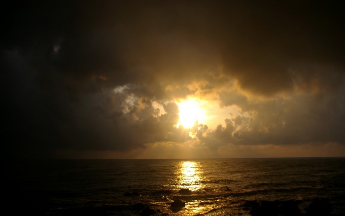 Sunset over the ocean with dark clouds
