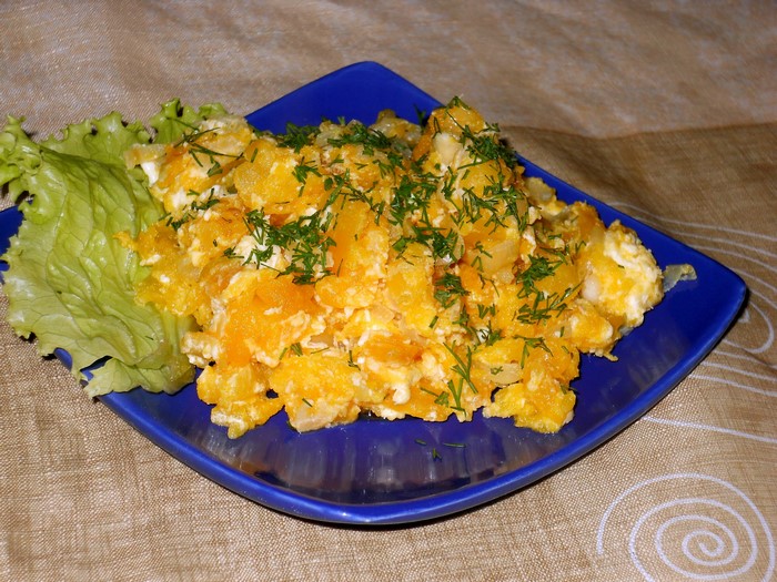 Scrambled eggs with pumpkin and dill on a blue plate