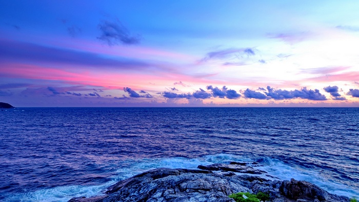 Ocean waves crash on rocky shore at sunset