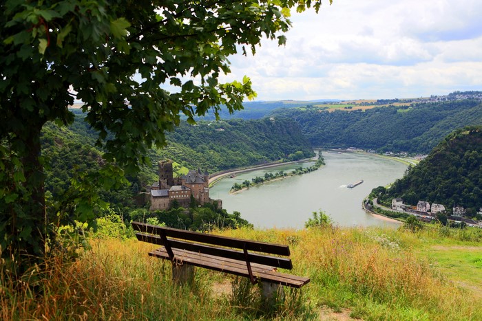 Castle overlooking a river valley with a bench in the foreground