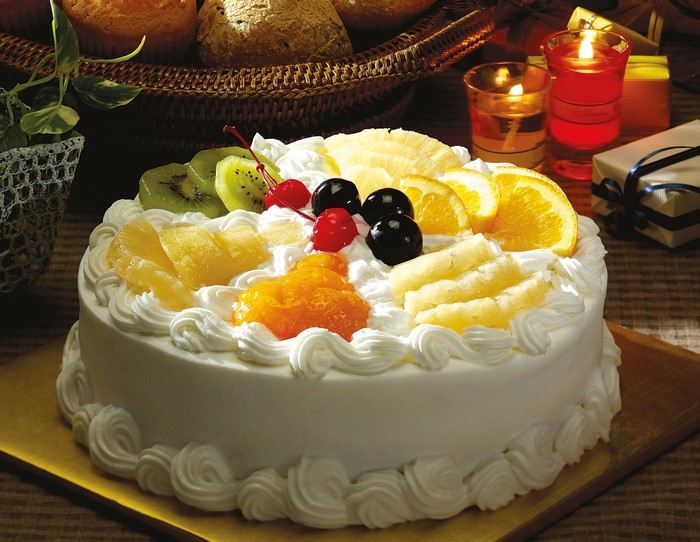 Fruit cake with whipped cream and candles