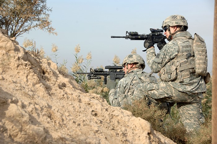 Soldiers in camouflage aiming rifles
