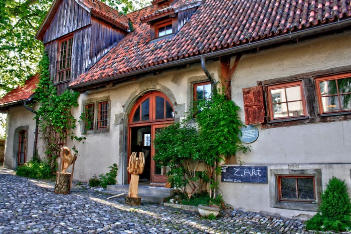 Art gallery entrance with wooden sculptures and cobblestone street