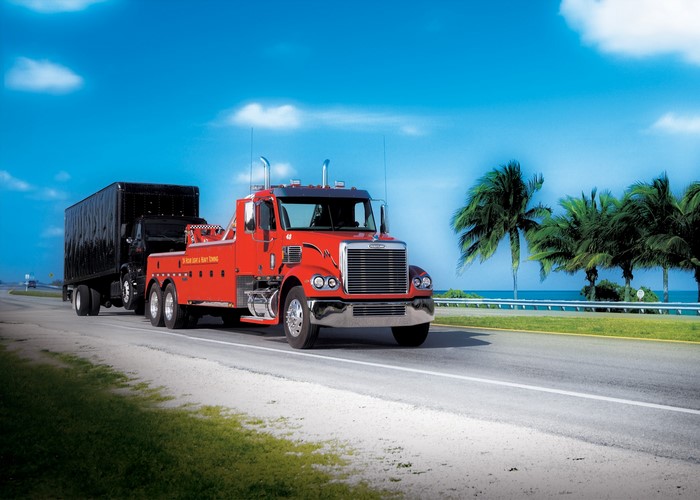 Red Freightliner Tow Truck towing a black trailer