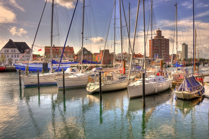 Sailboats docked in a harbor with buildings in the background