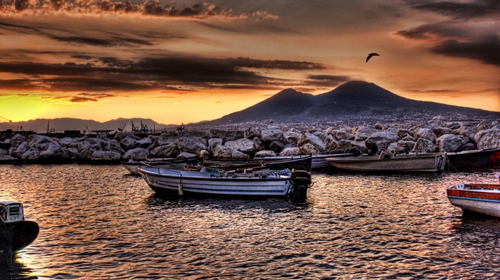 Boats in harbor with Mount Vesuvius at sunset