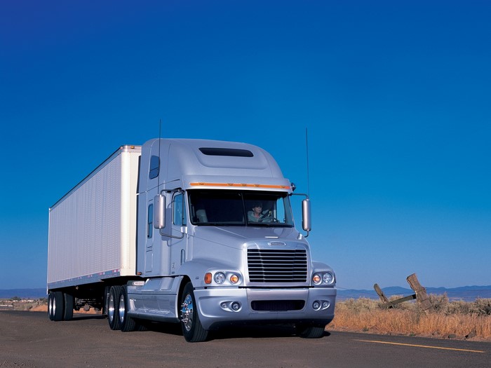 Silver Freightliner semi-truck with trailer on a road