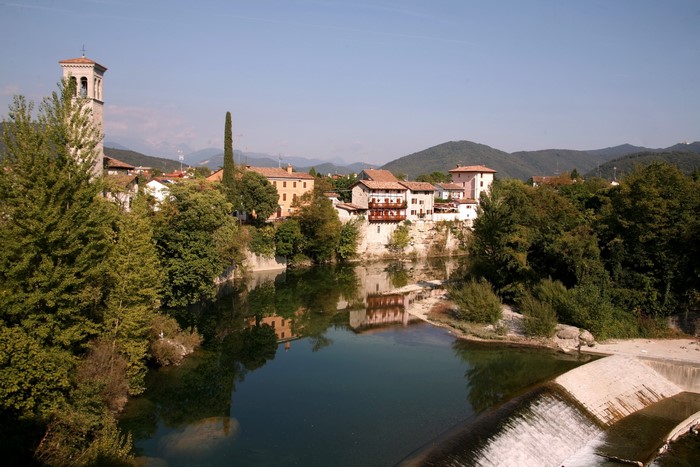 Town with bell tower on river in Cividale, Italy