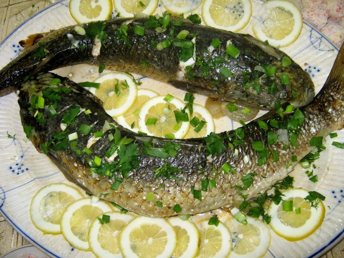 Two whole cooked fish garnished with lemon and herbs