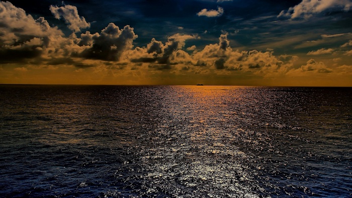 Ship on the ocean at sunset with dramatic clouds