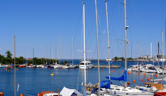 Sailboats and yachts docked in a harbor under a clear blue sky