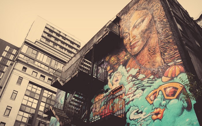 Graffiti mural of a woman's face and sunglasses on a building