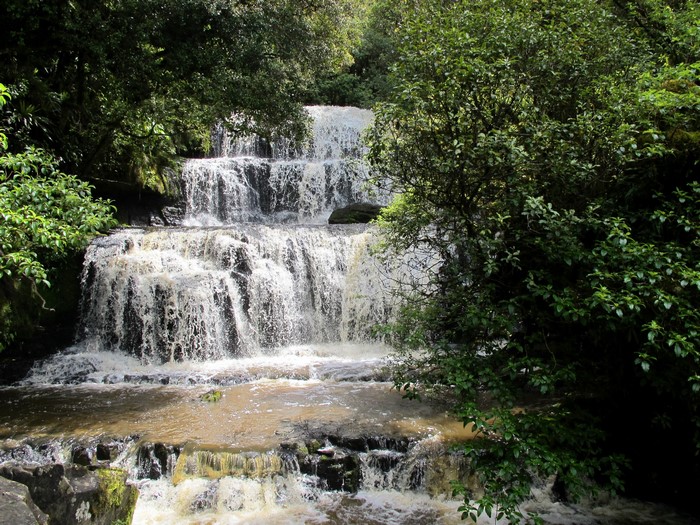 Multi-tiered waterfall surrounded by lush green foliage