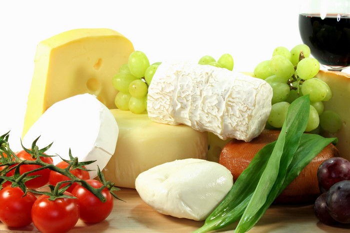 Cheese platter with grapes, tomatoes, and red wine