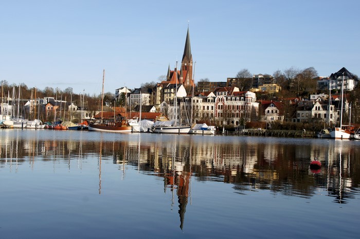 Boats docked in a harbor with a German town in the background