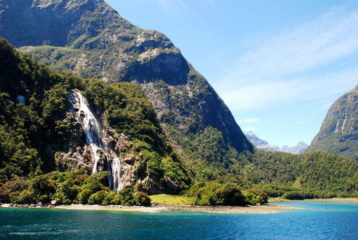 Waterfall cascading down a mountain into a blue lake