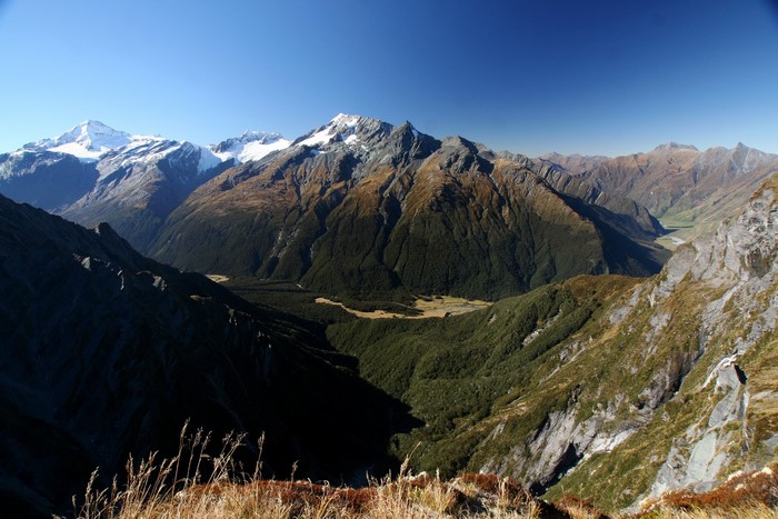 Mountain range with snow-capped peaks and forested valleys