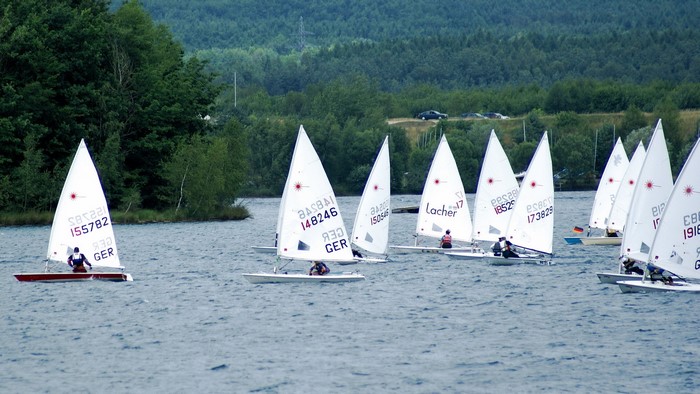 Sailboats racing on a lake with a forest background