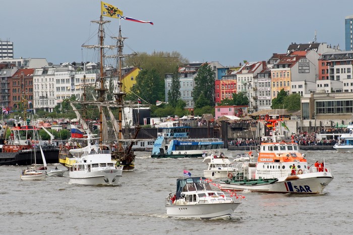 Ships sailing in a harbor with buildings in the background