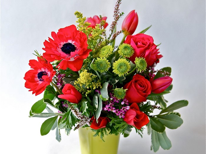 Red and pink floral arrangement in a lime green vase