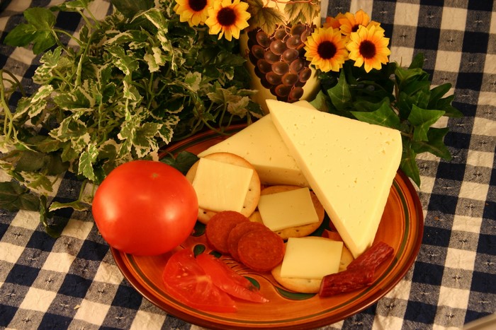 Cheese, crackers, tomato, and pepperoni on a plate