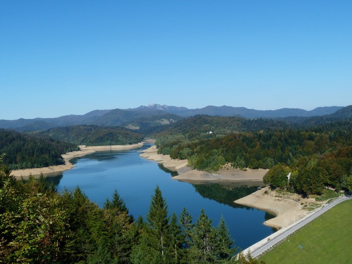 Lake and forested hills under a clear blue sky