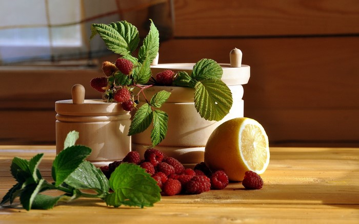 Raspberries, mint, lemon, and wooden jars