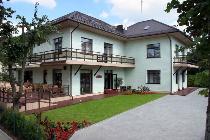 Light green building with balconies and outdoor seating