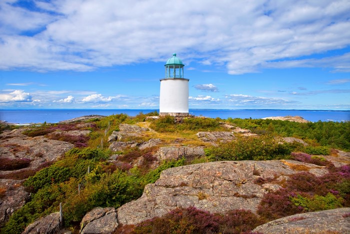 White lighthouse on a rocky coast with the sea and sky