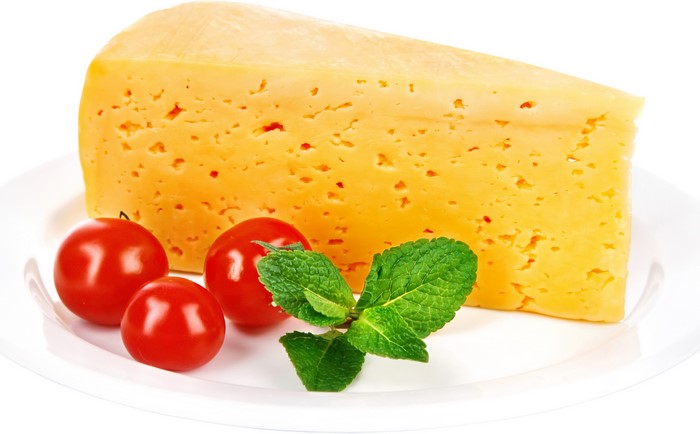 A wedge of cheese with cherry tomatoes and mint