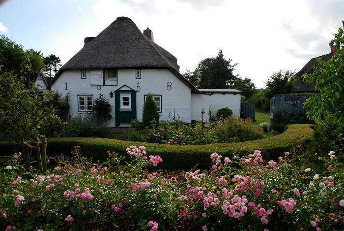 White brick house with thatched roof and garden in Germany