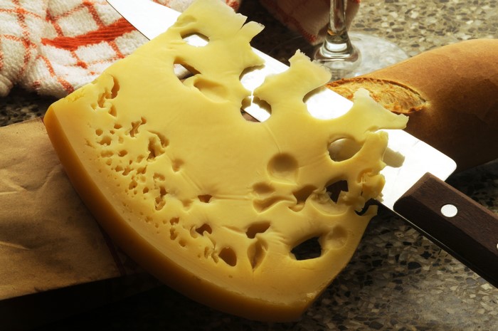 Slice of Swiss cheese with holes on a knife