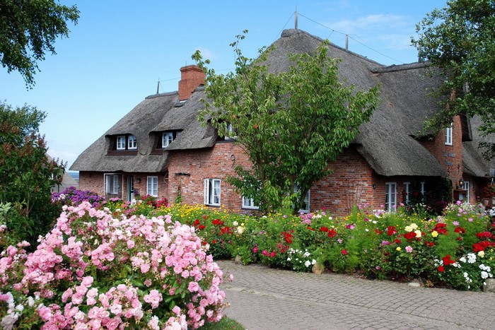 Thatched roof house with colorful flower garden in Germany