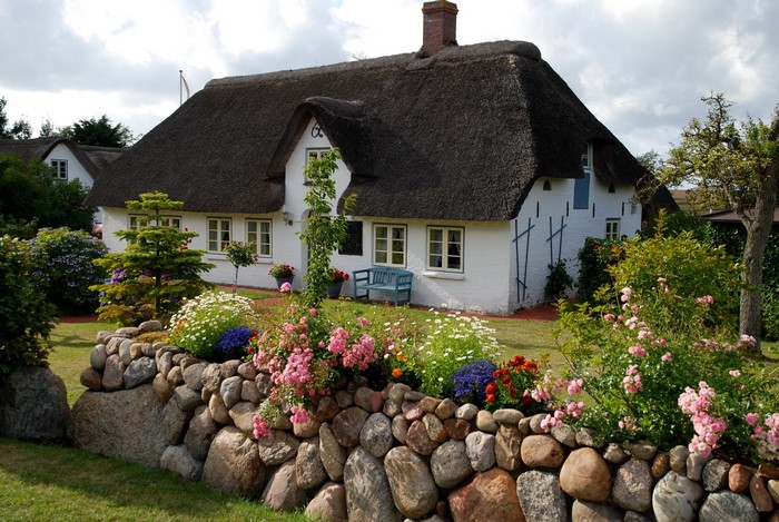 Thatched roof house in Germany with stone wall and flowers