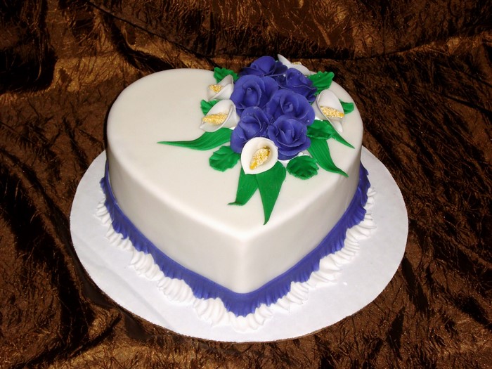Heart-shaped cake with blue roses and white calla lilies