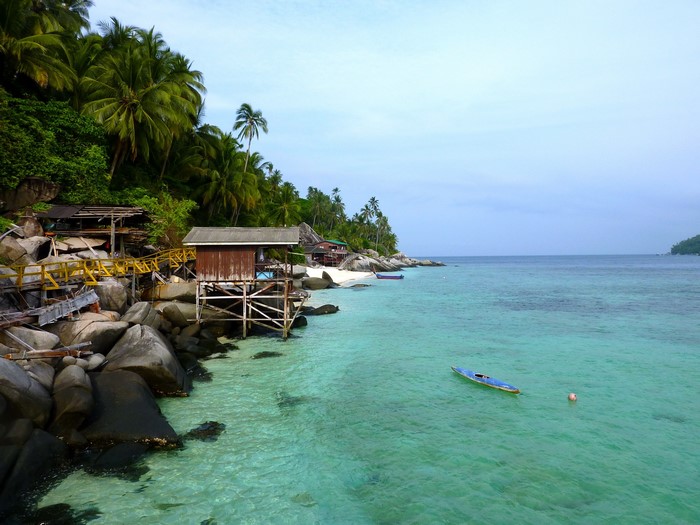 Tropical beach with stilt houses and clear turquoise water