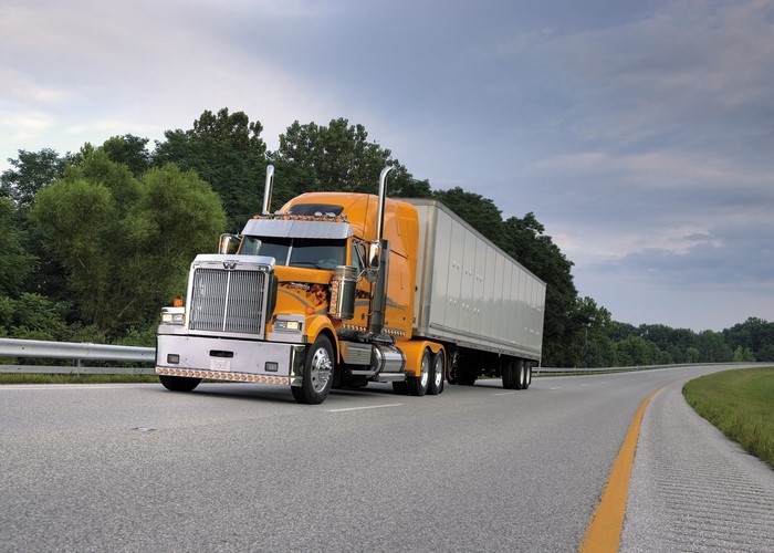 Orange Western Star Truck driving on a highway