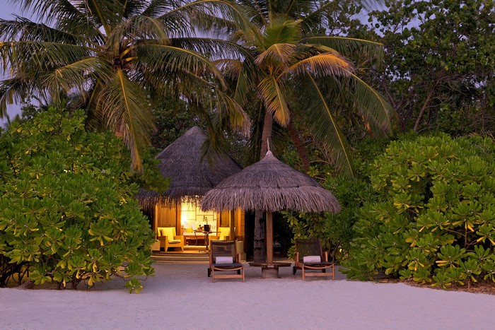 Tropical beach resort with thatched bungalows and palm trees