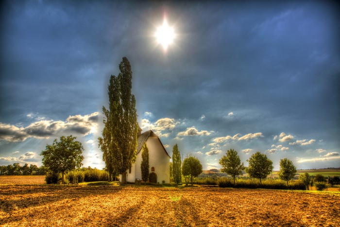 White church in a field under a dramatic sky