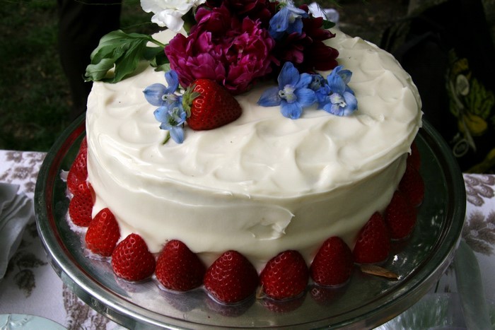 White frosted cake with strawberries and flowers