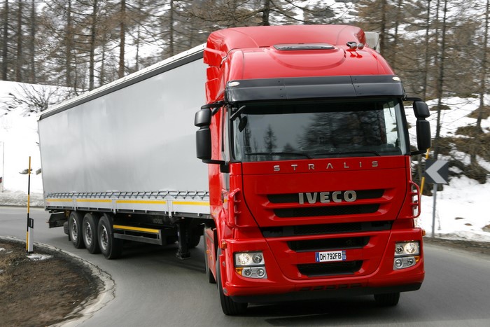 Red Iveco Stralis Truck with Trailer on Snowy Road