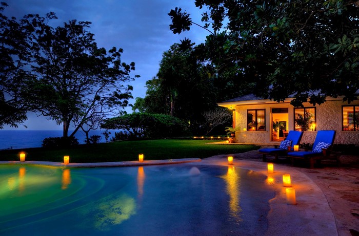 Resort pool at night with candles and lounge chairs