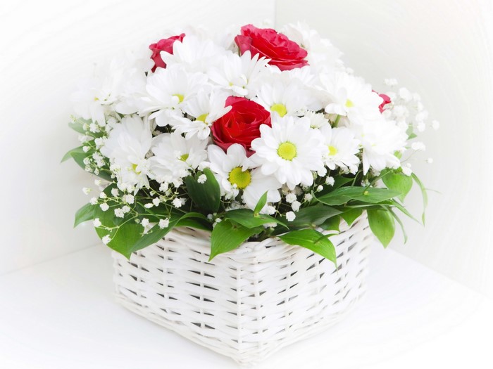White camomiles and red roses in a white basket