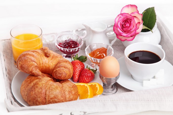 Breakfast tray with croissants, fruit, coffee, and jam