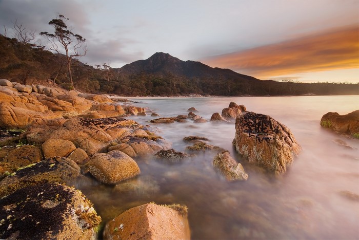 Rocky coastline with mountain and sunset sky