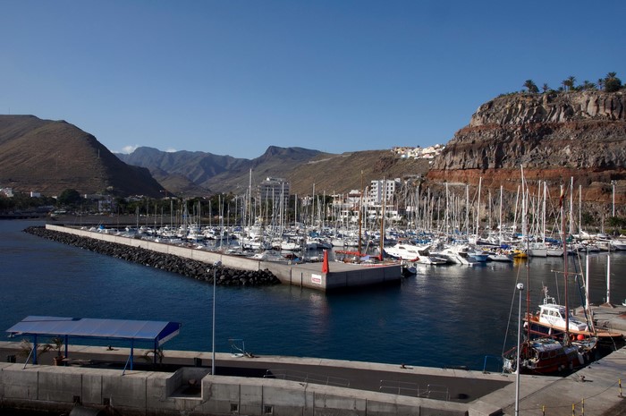 Boats docked in a harbor with mountains in the background
