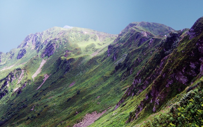 Green mountain slopes under a clear sky