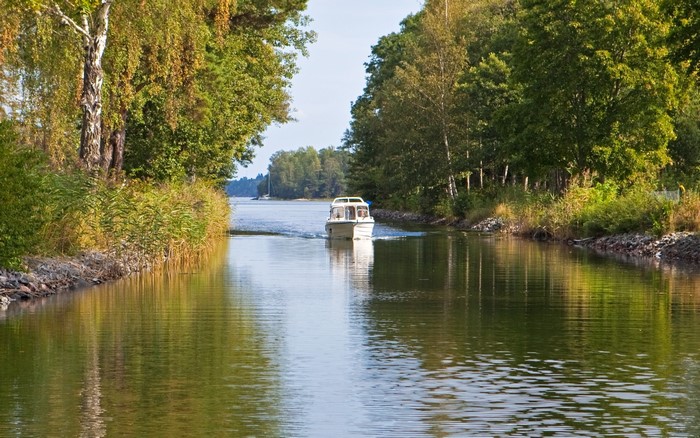 Boat traveling on a canal surrounded by trees