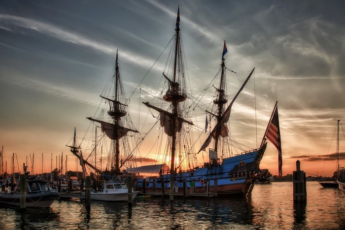 Tall ship docked at harbor during sunset