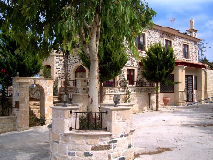 Stone house with trees and arched entrance in Greece
